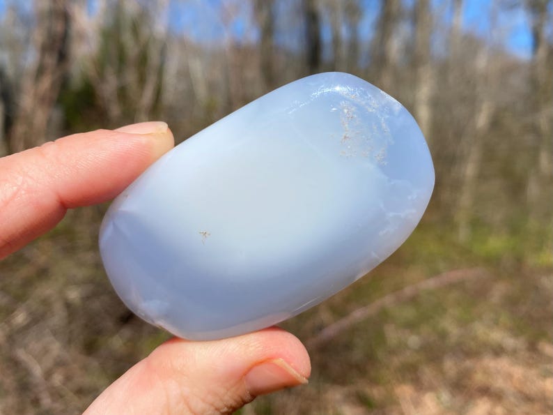 May include: A smooth, light blue and white agate stone with a rounded, oval shape.