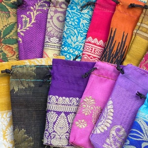 May include: Assortment of colorful fabric drawstring pouches with various patterns and designs. The pouches are made of silk and are perfect for storing small items.