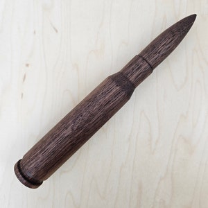 May include: A dark brown wooden rolling pin shaped like a bullet.