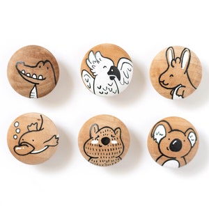 May include: Six wooden knobs with painted Australian animals. The knobs feature a crocodile, a cockatoo, a kangaroo, a platypus, a wombat, and a koala.