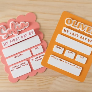 Könnte beinhalten: Zwei personalisierte Schultafeln. Die linke Tafel ist rosa, gewellt und trägt die Aufschriften Sofia, My First Day Of, Teacher, Age, My Favorite Things und When I Grow Up I Want To Be. Die rechte Tafel ist orange und zeigt Oliver, My Last Day Of, Height, Date, Age und When I Grow Up I Want To Be.