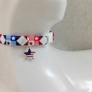 May include: A patriotic pet collar with a red, white, and blue star and diamond pattern. The collar has a white plastic buckle and a silver star-shaped charm with a flag design. This accessory is perfect for showing off your pet's American pride.