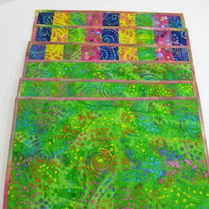 May include: Set of six colorful placemats with a green background and a pattern of swirls and dots. The placemats have a pink border.