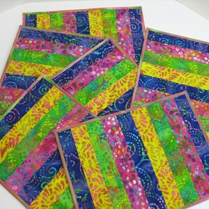 May include: Set of six colorful placemats with a striped pattern in shades of pink, yellow, green, and blue. The fabric has a batik design with swirls and dots.