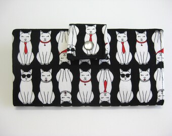 May include: Black fabric wallet with a white cat pattern. The cats are wearing sunglasses, ties, and collars. The wallet has a snap closure.