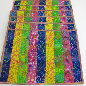 May include: Set of six colorful placemats with a striped pattern in shades of blue, green, yellow, and pink. The placemats are made of fabric with a batik design.