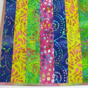 May include: A colorful fabric quilt with vertical stripes in shades of blue, yellow, green, and pink. The fabric has a batik pattern with various shapes and designs.