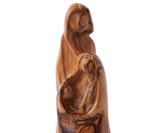 May include: A wooden sculpture of the Holy Family, carved from olive wood. The sculpture depicts Mary, Joseph, and baby Jesus in a close embrace.