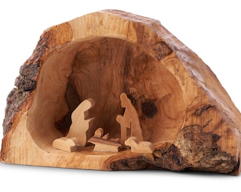 May include: A wooden nativity scene carved into a tree trunk. The figures are simple silhouettes of Mary, Joseph, the baby Jesus, and a sheep.