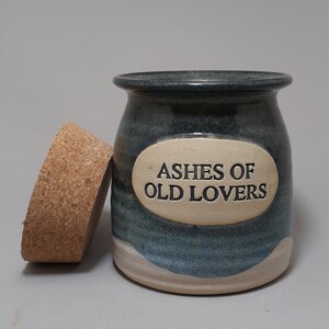 May include: A blue and white ceramic jar with a cork lid. The jar has a white oval label with the text "Ashes of Old Lovers".