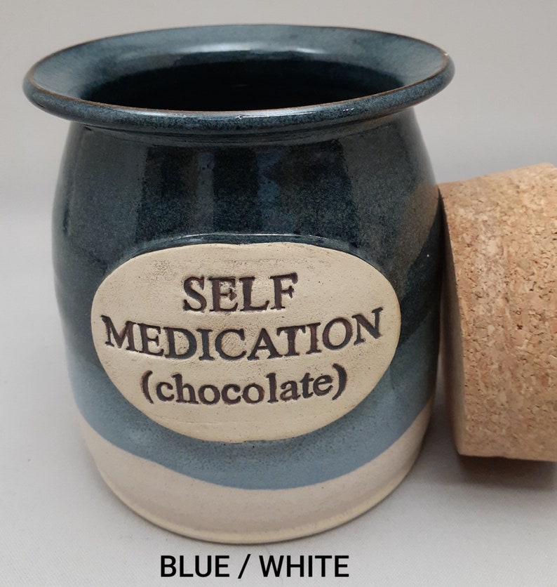 Puede incluir: Tarro de cer&aacute;mica azul y blanco con tapa de corcho. El tarro tiene una etiqueta ovalada blanca con el texto "SELF MEDICATION (chocolate)".