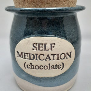 Puede incluir: Tarro de cer&aacute;mica azul y blanco con tapa de corcho. El tarro tiene una etiqueta ovalada blanca con el texto "SELF MEDICATION (chocolate)".