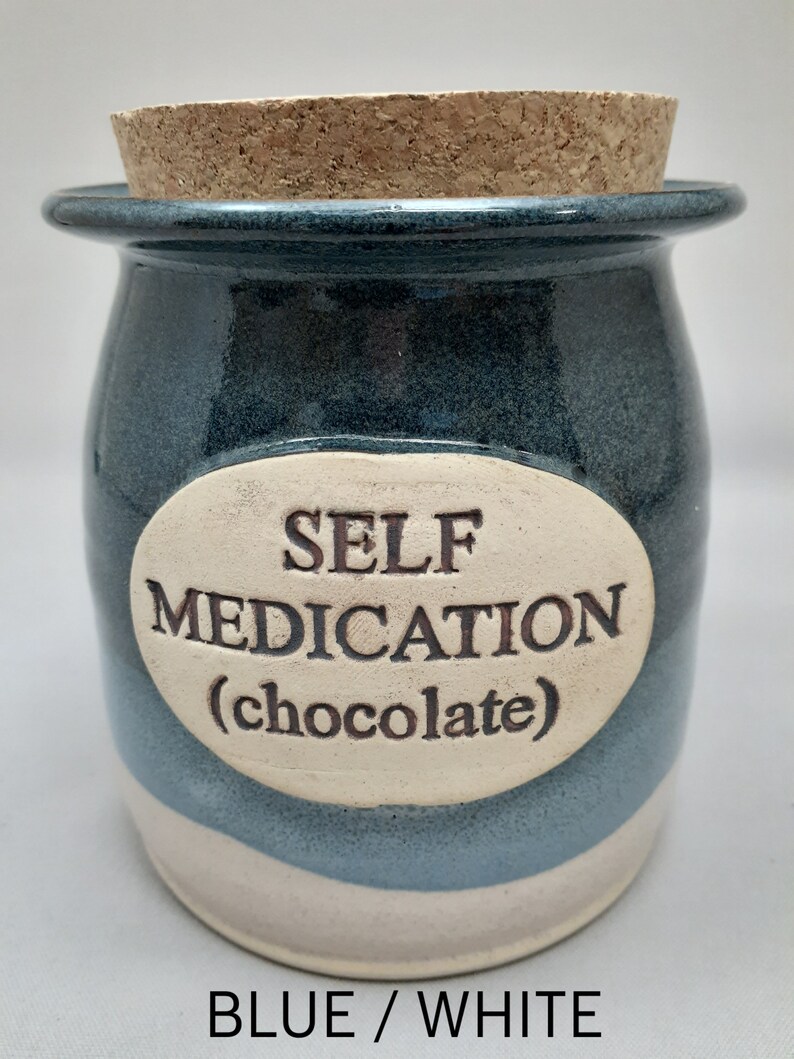 Puede incluir: Tarro de cer&aacute;mica azul y blanco con tapa de corcho. El tarro tiene una etiqueta ovalada blanca con el texto "SELF MEDICATION (chocolate)".