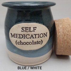 Puede incluir: Tarro de cer&aacute;mica azul y blanco con tapa de corcho. El tarro tiene una etiqueta ovalada blanca con el texto "SELF MEDICATION (chocolate)".