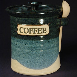 May include: A blue and white ceramic coffee jar with a wooden spoon attached to the side. The jar has a label that reads "COFFEE".