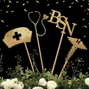May include: Gold glitter nurse graduation party decorations with a stethoscope, a nurse's hat, a caduceus, and the letters "BSN".