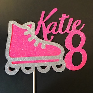 Könnte beinhalten: Rosa und silberner Glitzer-Rollschuh-Kuchentopper mit dem Namen "Katie" und der Zahl "8" darauf.