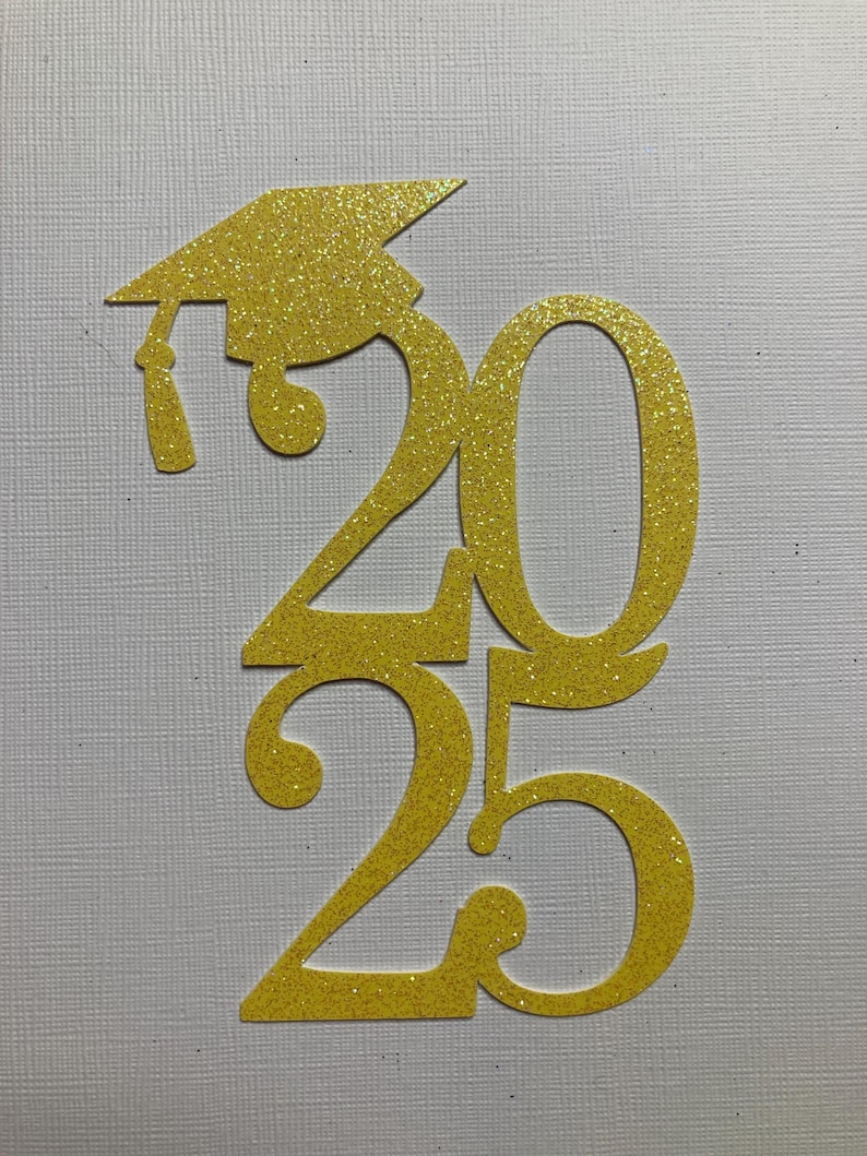 May include: Glittery gold graduation cap and the numbers 2025, cut from a textured material. The cap is positioned above the number 2, with the tassel hanging down. The numbers are stacked vertically, with the 20 on top and the 25 below.