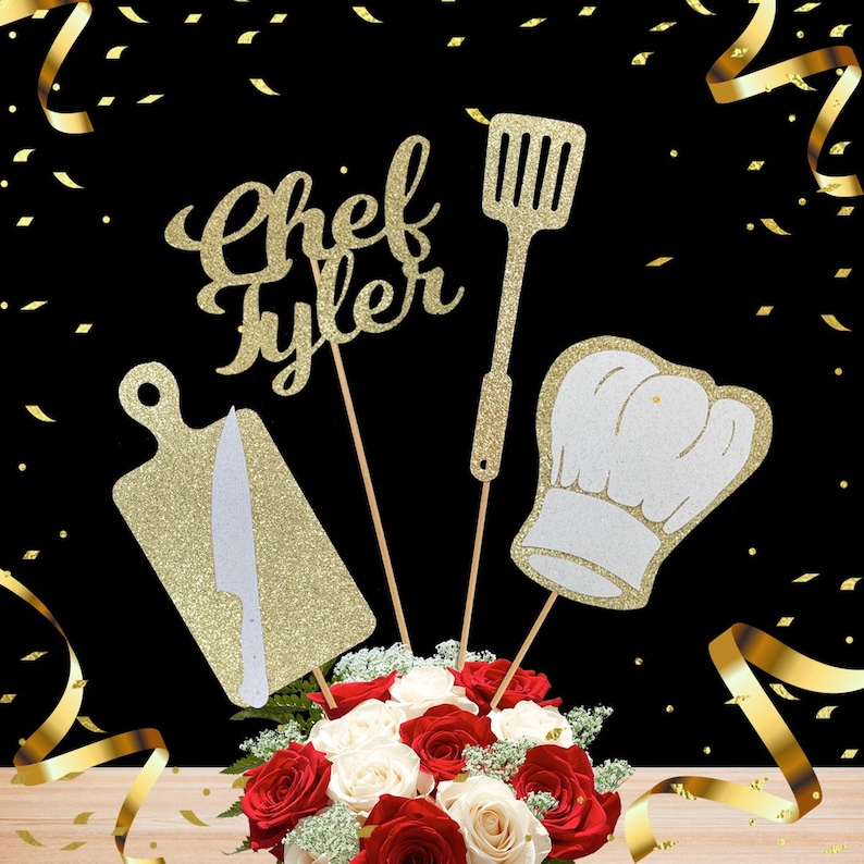 May include: Gold glitter 'Chef Tyler' cake topper featuring a chef's hat, a chopping board, and a spatula. The topper is displayed on a bouquet of red and white roses.