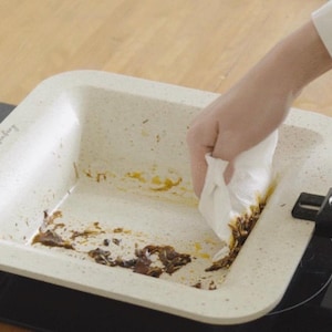 Puede incluir: Una fuente rectangular de horno blanquecina con textura moteada se limpia con una toalla de papel blanca. La fuente est&aacute; sobre una placa de cocina negra. El texto "Mr. Everyday" es visible.