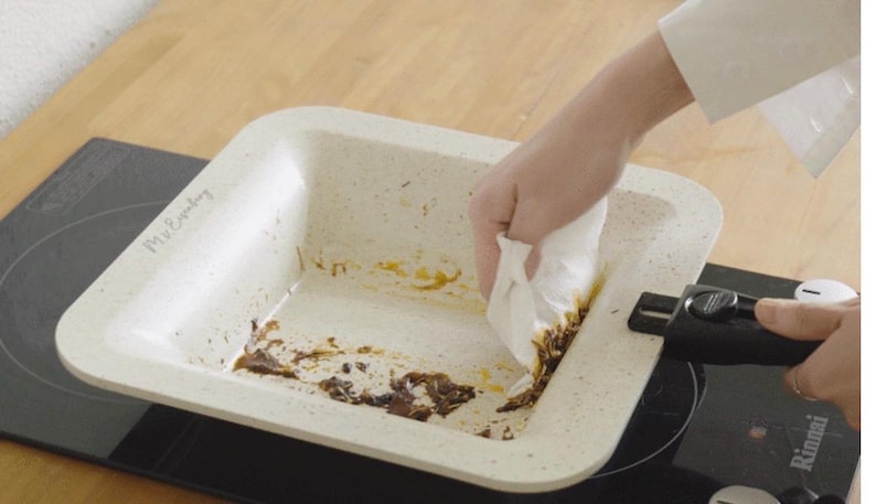 Puede incluir: Una fuente rectangular de horno blanquecina con textura moteada se limpia con una toalla de papel blanca. La fuente est&aacute; sobre una placa de cocina negra. El texto "Mr. Everyday" es visible.