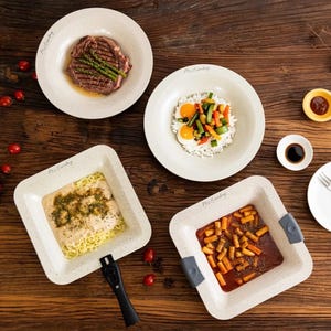 Puede incluir: Vista a&eacute;rea de una mesa de madera con cuatro platos de comida. Los platos beige llevan el texto "Mr. Eatsby". La comida incluye bistec con esp&aacute;rragos, arroz con verduras y huevos, pasta y un plato con salsa roja y trozos de naranja.