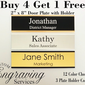 May include: Buy 4 get 1 free, 2 inch by 8 inch door plates with holders.  The plates are black, silver, and gold with black lettering.  The text on the plates reads "Jonathan, District Manager", "Kathy, Sales Associate", and "Jane Smith, Marketing".  The plates are for custom engraving services.