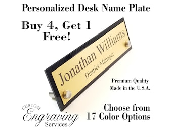 May include: A black and gold desk name plate with the text "Jonathan Williams, District Manager" engraved on it. The plate has a black border and gold lettering. The text "Buy 4, Get 1 Free!" is written above the plate. The text "Custom Engraving Services" is written below the plate. The text "Premium Quality Made in the U.S.A." is written below the plate. The text "Choose from 17 Color Options" is written below the plate.