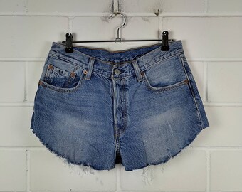 May include: Light blue denim shorts with a frayed hem. The shorts have a classic five-pocket design and a button fly.
