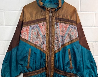 May include: A long-sleeve windbreaker jacket featuring a color-blocked design in teal, brown, and a central panel with a geometric pattern. The jacket includes a full-length front zipper, a high collar, two side pockets, and elasticized cuffs.
