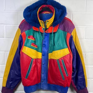 Peut inclure: Veste en cuir vintage aux couleurs vives. Elle présente une capuche doublée de fausse fourrure bleue, un col jaune et une fermeture boutonnée. Les couleurs incluent des panneaux rouges, jaunes, verts, violets et bleus.