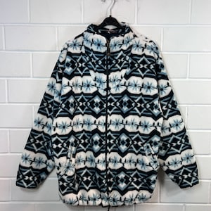 May include: A black, white, and blue patterned fleece jacket with a zipper closure. The jacket has a high collar and two pockets.