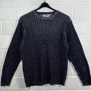 Könnte beinhalten: Ein schwarz-weiß gestreifter Pullover mit gerippter Struktur. Der Pullover hat einen Rundhalsausschnitt und lange Ärmel.