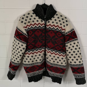 Könnte beinhalten: Ein cremefarbener, rot, schwarz und grauer gemusterter Strickpullover mit Reißverschluss.