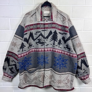 Könnte beinhalten: Ein Hemd mit Knöpfen und einem Muster in Grau, Schwarz und Burgunderrot. Das Design zeigt Berge, Hirsche und blaue Blumenmotive. Das Hemd hängt an einem schwarzen Kleiderbügel.