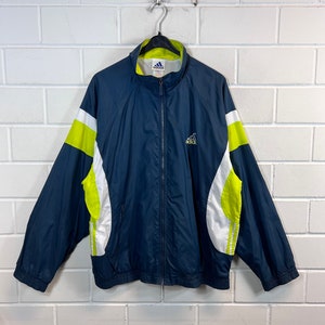 May include: A navy blue windbreaker jacket with white and neon green accents. The jacket has a zip fastening and a logo that says "adidas" on the left chest.