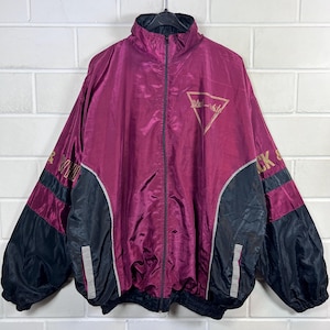 May include: A vintage burgundy and black track jacket with a full zip and a stand-up collar. The jacket features gold text and a triangular logo that reads "Black & White". The sleeves have black panels with burgundy stripes.