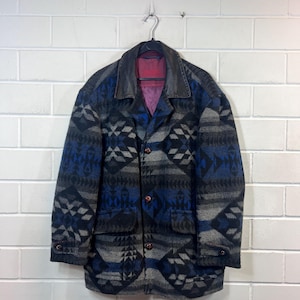 May include: A blue, gray, and black patterned jacket with a brown leather collar. The jacket has a button closure and two pockets.