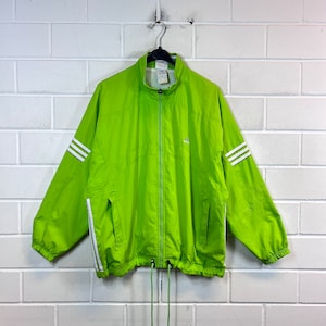 May include: A bright green windbreaker jacket with white stripes down the sleeves and a zip closure. The jacket has a drawstring at the bottom.