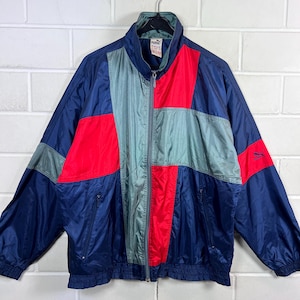 Pode incluir: Casaco desportivo Puma vintage com design de blocos de cores. O casaco apresenta painéis em azul marinho, vermelho e cinza. Possui fecho de correr completo, gola alta e o logótipo Puma no peito. O casaco é feito de um material leve, possivelmente nylon.