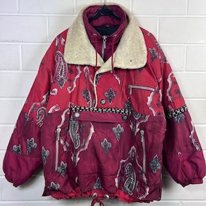 May include: A vintage red and burgundy anorak jacket with a paisley pattern and a cream-coloured faux fur collar. The jacket features a half-zip closure, a front pocket, and decorative zips. The jacket has a drawstring at the bottom.
