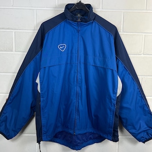 May include: A blue and navy blue zip-up jacket with a white Nike logo on the chest. The jacket has a high collar and a full-length zip. The sleeves and shoulders are navy blue, while the body is a vibrant blue.