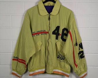 May include: A yellow bomber jacket with red and black accents. The jacket has the text "Los Angeles Air Racing" and the number "46" printed on the front. The jacket also has a small logo on the left side of the chest.