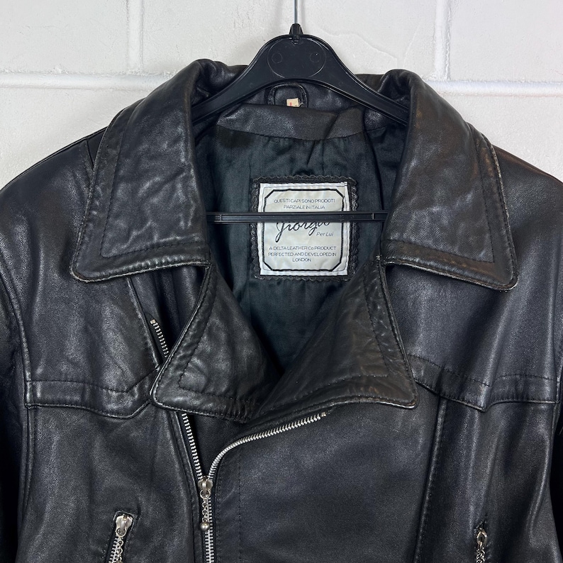 May include: Black leather jacket with a notched collar and a zipper closure. The jacket has a label that reads "Giorgio" and "A Delta Leather Product, Perfected and Developed, London."