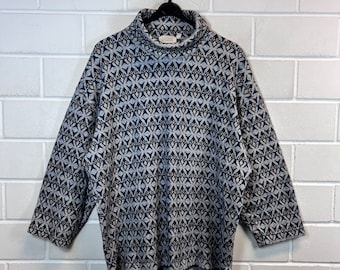 May include: A gray and blue patterned turtleneck sweater with a relaxed fit. The sweater has a geometric pattern with a subtle sheen.