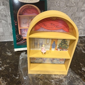 Puede incluir: Adorno de estantería amarillo en forma de arco con una bailarina en miniatura con un vestido rosa. El adorno está decorado con una escena del ballet "El Cascanueces" y viene con su caja verde original.