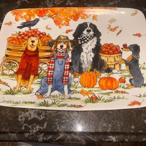 May include: Rectangular ceramic serving platter with a fall harvest theme. The illustration features dogs dressed in autumn attire, pumpkins, apples, and a crow. The color palette includes orange, brown, and green.