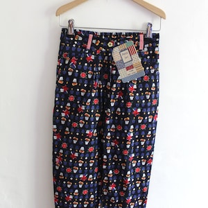 Puede incluir: Un pantalón azul, negro, rojo y amarillo estampado con una etiqueta de Petit Jac. El pantalón tiene cintura alta y largo recortado.