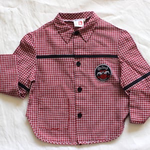 Op de afbeelding: Langarmhemd met rood-witte ruitjes, zwarte bies en een patch met de tekst "Oxford University" op de linkerborst.