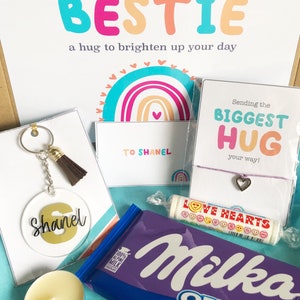 May include: A gift box with a variety of items, including a keychain, a bracelet, a chocolate bar, a candle, and a candy roll. The box has a card that says "Sending my BESTIE a hug to brighten up your day". The keychain has the name "Shanel".